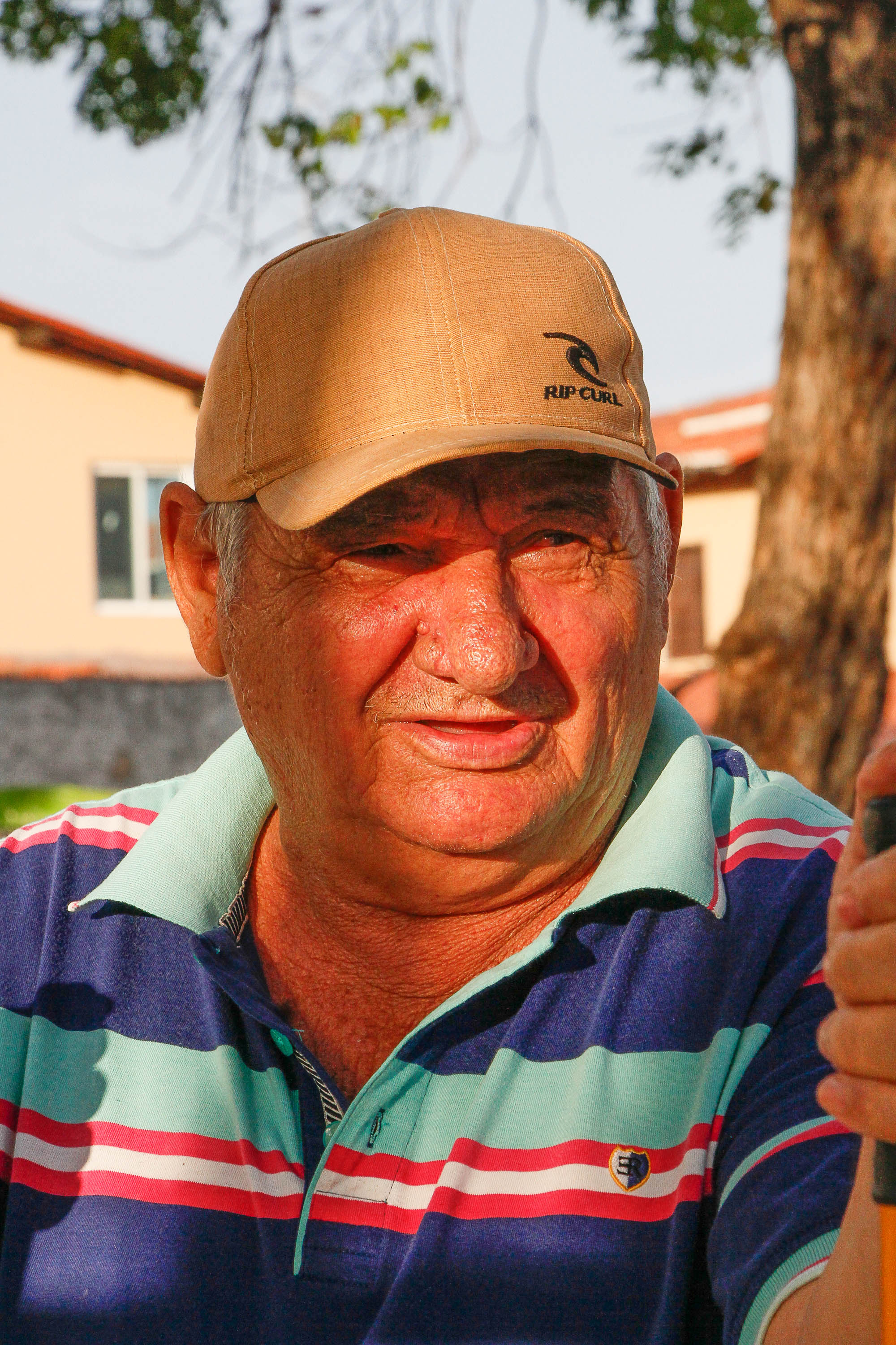 senhor de boné sorrindo para a foto